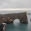 ARCHE DE DYRHÓLAEY - CÔTE SUD ISLANDAISE Wall decor photo of Dyrhólaey natural arch in Iceland showing black cliff and ocean under dramatic sky, perfect for Nordic interior decoration
