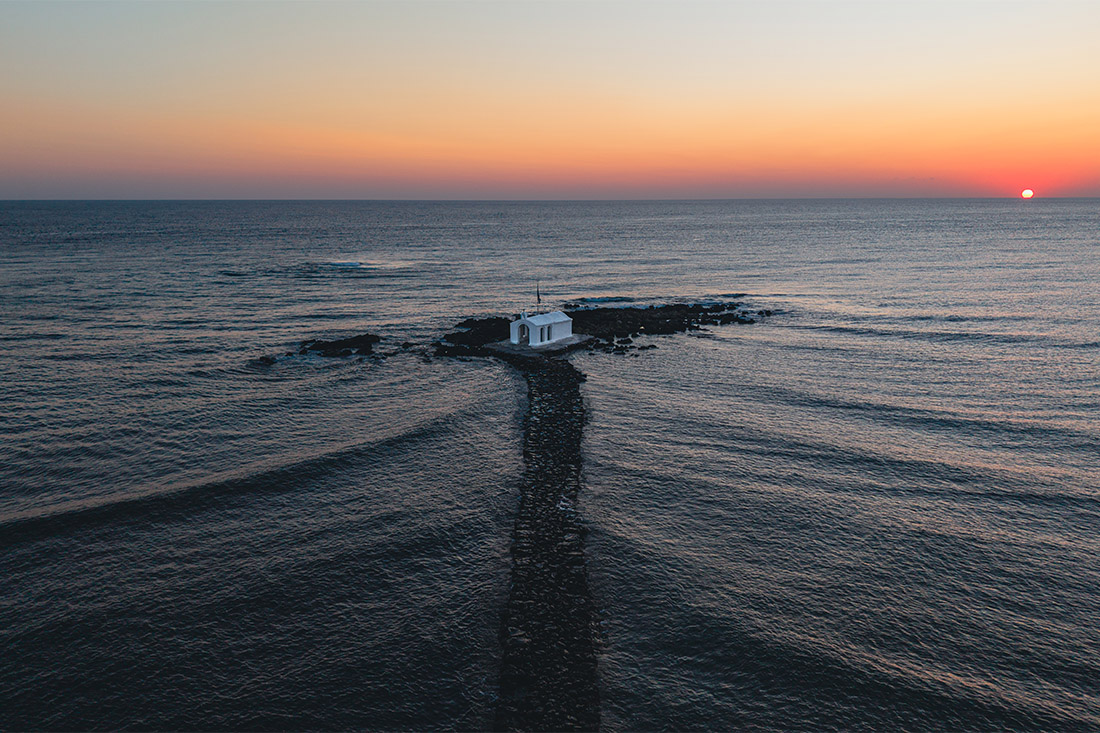 Chapel of Agios Nikolaos at sunrise, white chapel on a rocky islet with a stone causeway, Georgioupoli, Crete, Greece