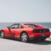 Red Ferrari 348 TS parked facing the ocean on 17-Mile Drive at Pebble Beach, California, rear three-quarter view