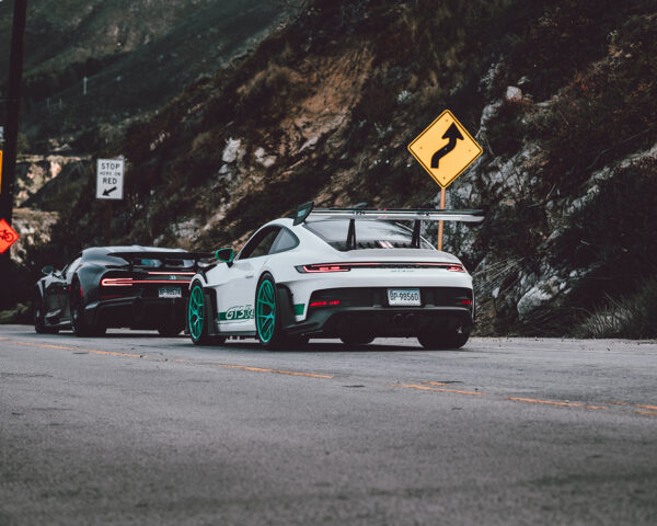 Wall decor photo of white Porsche GT3 RS with teal wheels and black Bugatti Chiron on canyon road, perfect for luxury automotive interior decoration