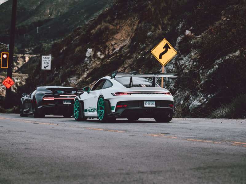 Wall decor photo of white Porsche GT3 RS with teal wheels and black Bugatti Chiron on canyon road, perfect for luxury automotive interior decoration