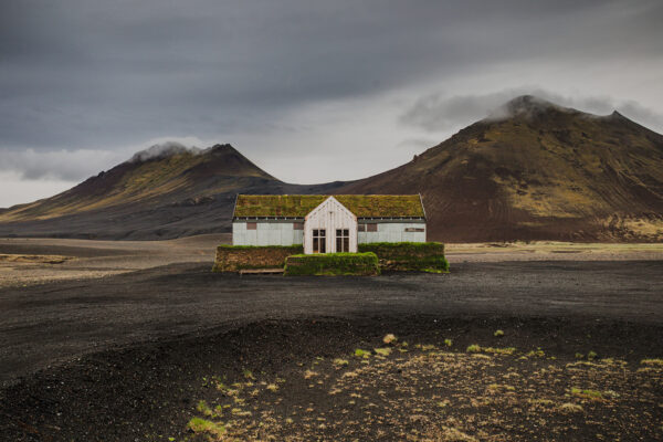Solitary moss-covered restaurant in the volcanic highlands of northeast Iceland near Möðrudalsleið with dramatic mountains