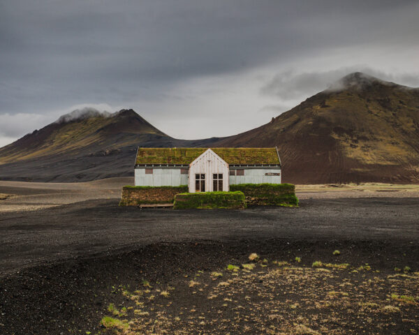 Solitary moss-covered restaurant in the volcanic highlands of northeast Iceland near Möðrudalsleið with dramatic mountains
