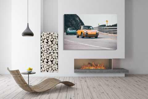 Wall decor photo of classic orange Porsche 911 on winding coastal road followed by a turquoise Porsche, perfect for vintage automotive interior decoration