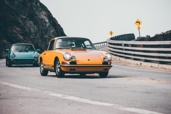 Photo Duo Porsche 911 Classic Pebble Beach Wall decor photo of classic orange Porsche 911 on winding coastal road followed by a turquoise Porsche, perfect for vintage automotive interior decoration