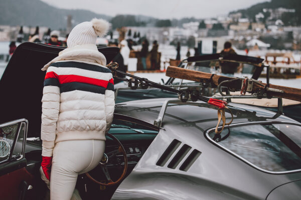 Ferrari 275 GTB photography showing a person in white winter attire with ski gear mounted on a classic silver Ferrari at the St. Moritz Concours d'Elegance 2023