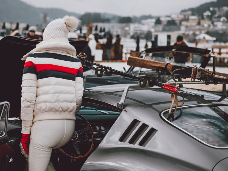 Ferrari 275 GTB photography showing a person in white winter attire with ski gear mounted on a classic silver Ferrari at the St. Moritz Concours d'Elegance 2023