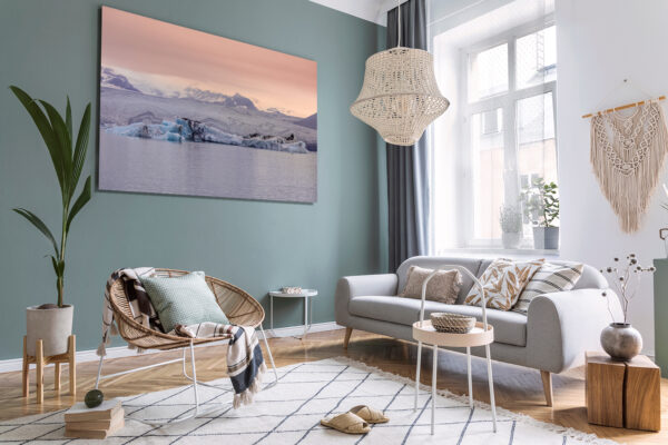 Boho interior design of living room with sofa and rattan armchai Wall decor photography of Jökulsárlón glacier in Iceland showing azure blue icebergs floating on the glacial lagoon under a pink twilight sky, perfect for Scandinavian interior design