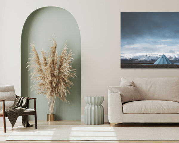 Svalbard photography showing a solitary blue tipi tent facing snow-capped mountains of the arctic fjords under a dramatic sky