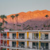 The Saguaro Hotel with colorful pink orange yellow facades at sunset with San Jacinto Mountains and palm trees in Palm Springs California