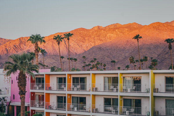 The Saguaro Hotel with colorful pink orange yellow facades at sunset with San Jacinto Mountains and palm trees in Palm Springs California