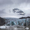Dramatic landscape photograph of Svinafellsjökull Glacier in Vatnajökull National Park, Iceland, showcasing blue ice formations against dark mountains under a moody sky