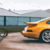 Yellow Porsche 930 Turbo S Fine Art Photography | Cars and Roses Yellow Porsche 930 Turbo S fine art photography print, rear three-quarter view beside a vintage red fuel pump and corrugated hangar, Cars and Roses