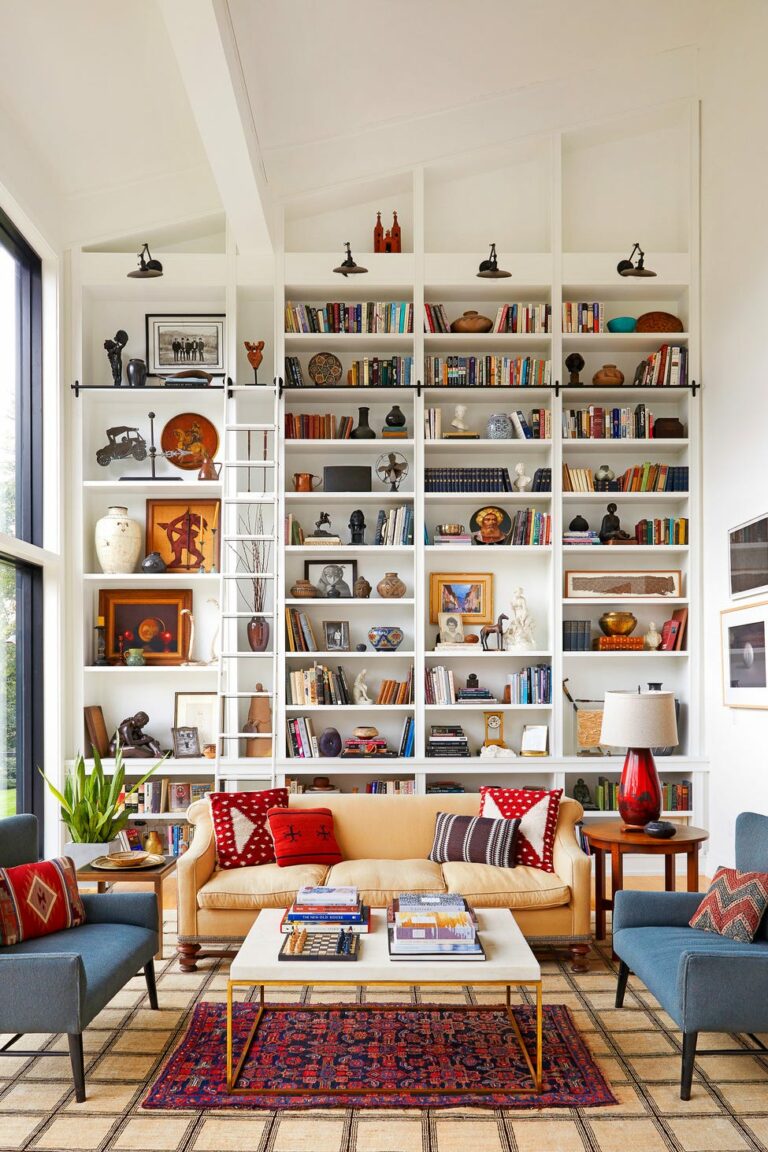 Luxurious living room with a tall white built-in bookshelf wall, a ladder, and a beige sofa, showcasing modern wall decor ideas and colorful accents.
