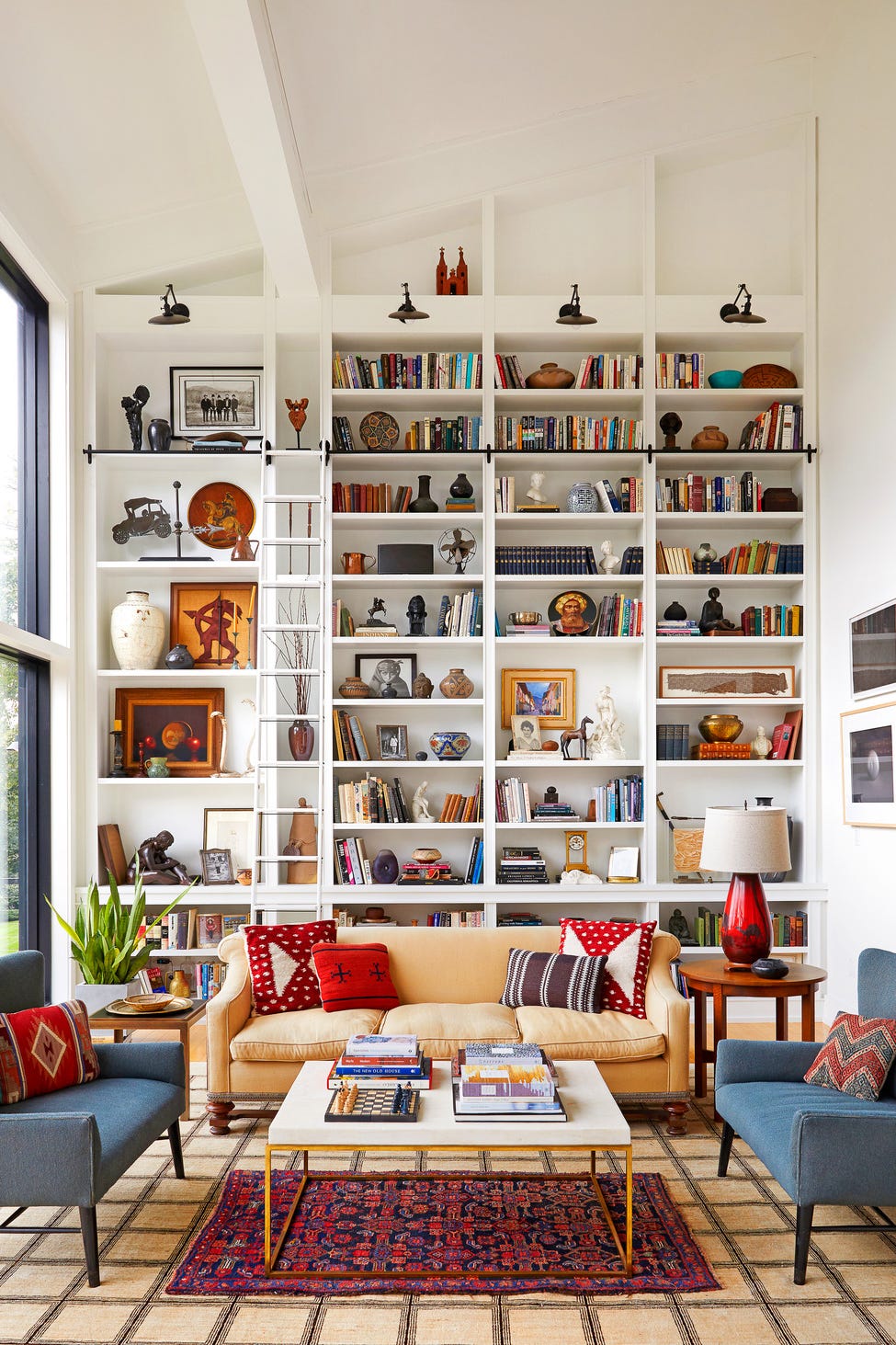 Luxurious living room with a tall white built-in bookshelf wall, a ladder, and a beige sofa, showcasing modern wall decor ideas and colorful accents.