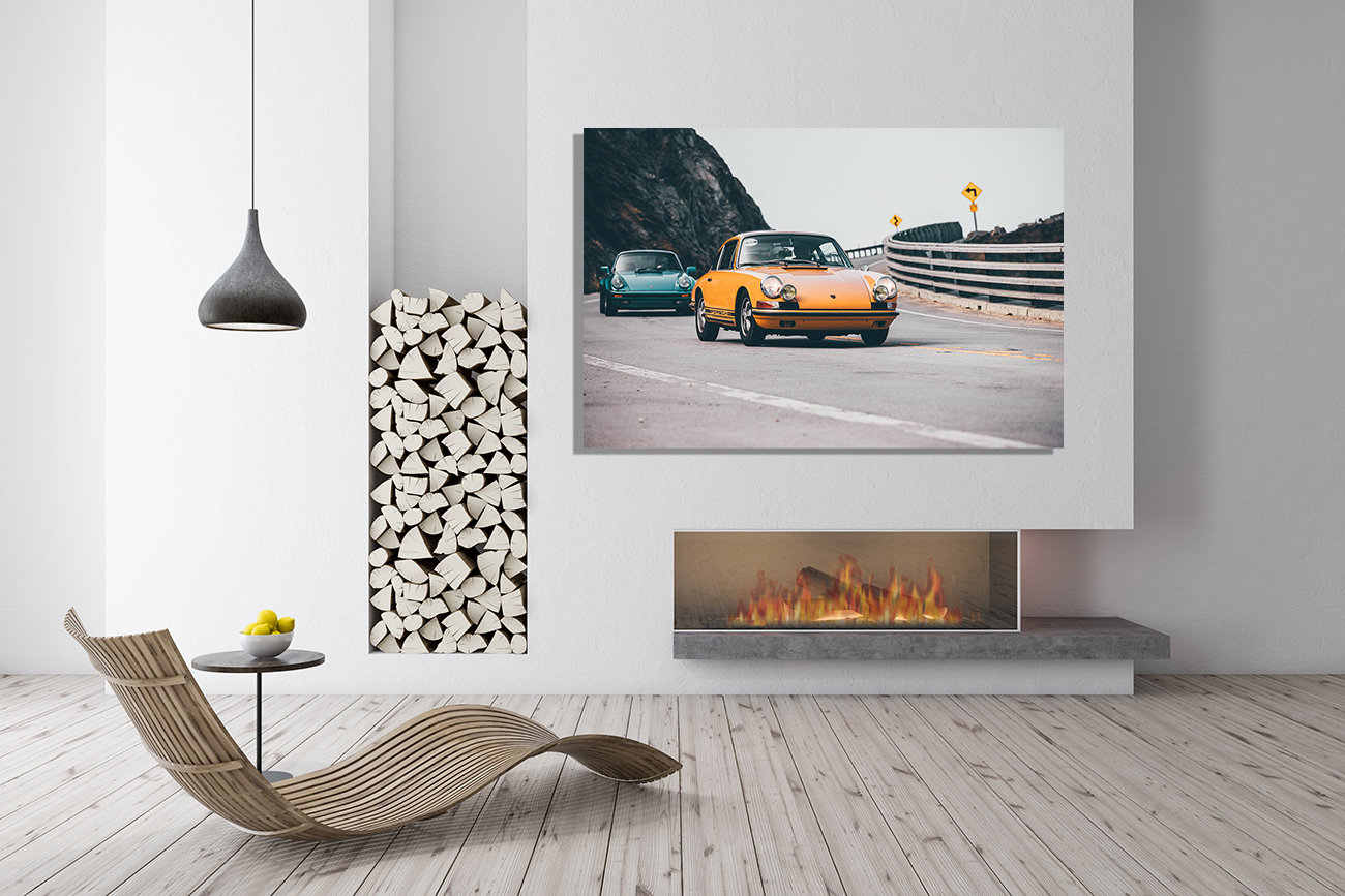 Modern wall decor ideas: a minimalist living area with a large framed car photo above a linear fireplace, a wood stack sculpture, and a curved lounge chair beside a small side table.