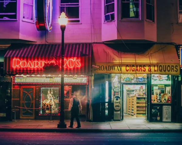 san-francisco-nuit-broadway-v2-900x600-1.webp Fine art photograph of Broadway in San Francisco at night: red Roaring 20’s neon sign, lit street lamp and a passer-by in motion